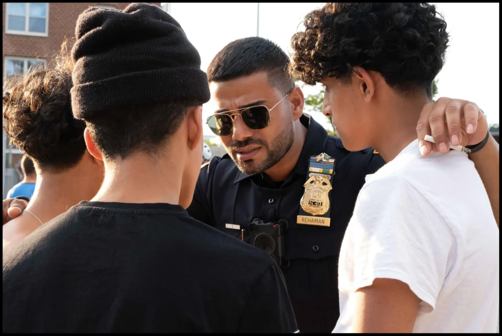 Cops and Kids Image of a police officer huddled around three teenage boys